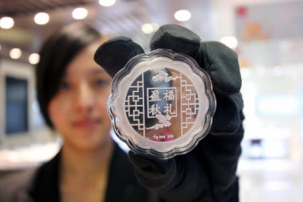 A sales girl displaying a silver 'mooncake' in a shop in China. Photo: AFP