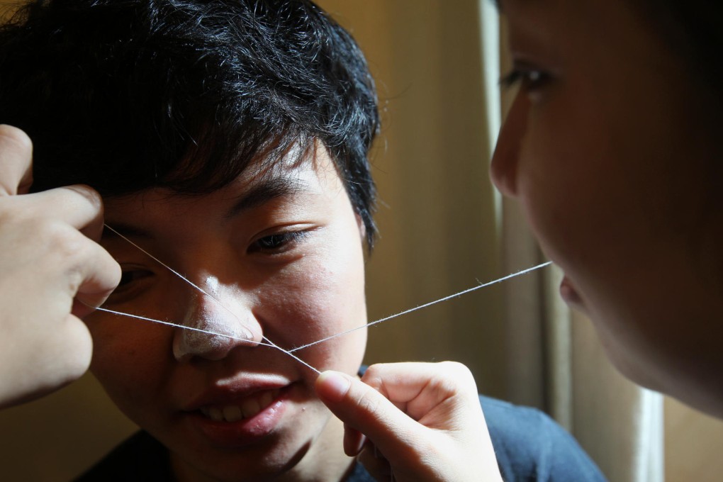 Beautician Chong Sui-ko (right) is equipped with an array of modern cosmetic skills, but uses the ancient method of threading to remove her customers' facial hair. Photo: May Tse
