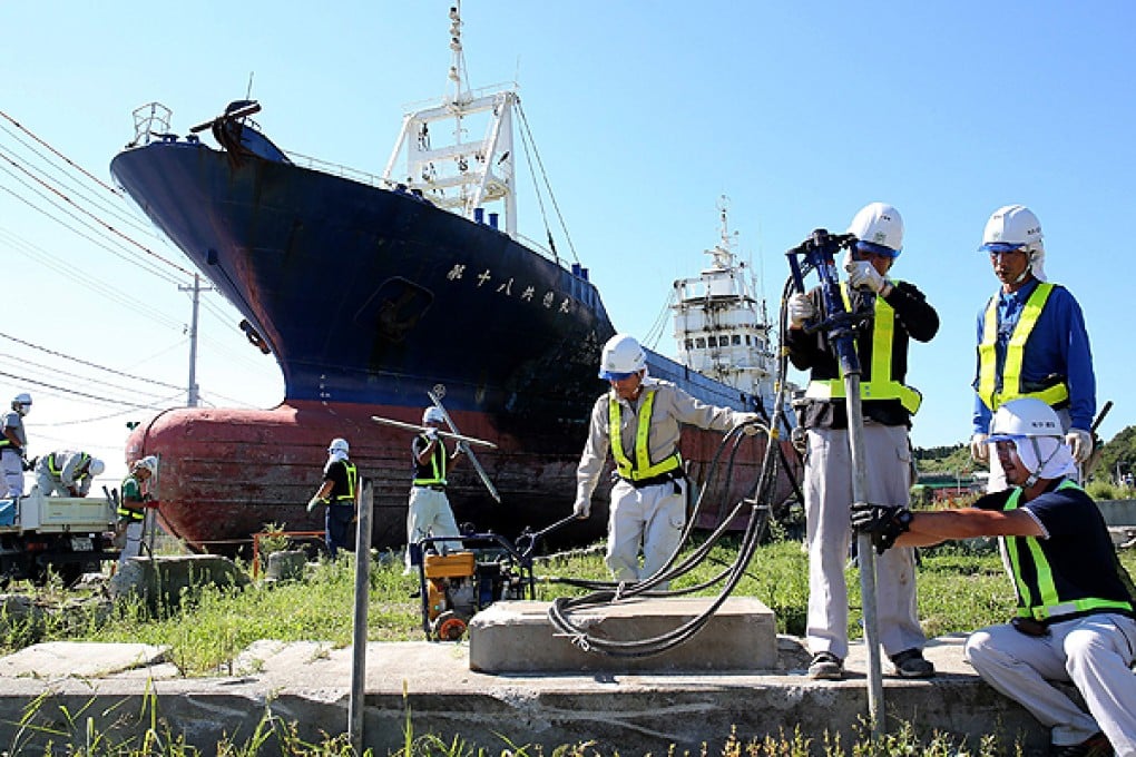 Workers prepare to scrap the fishing boat Kyotoku-maru in Kesennuma city, Miyagi prefecture. Photo: AFP