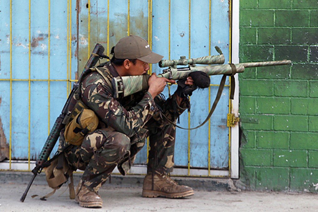 A government soldier looks through the scope of his rifle as residents believed to be hostages of Moro National Liberation Front rebels shout to the soldiers to "stop firing" in central Zamboanga city, in southern Philippines on Wednesday. Photo: Reuters