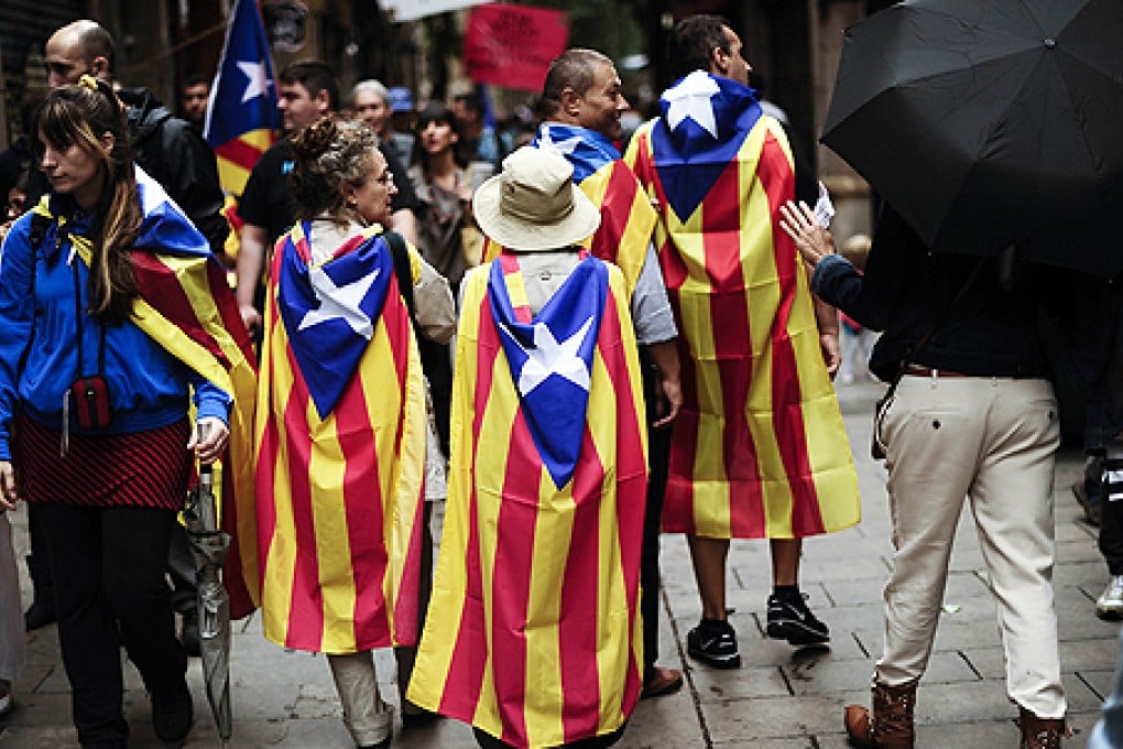 People walk wrapped in Catalonia's flag 'Estelada' during celebrations for Catalonia National Day, or Diada, in Barcelona on Wednesday. Photo: AFP