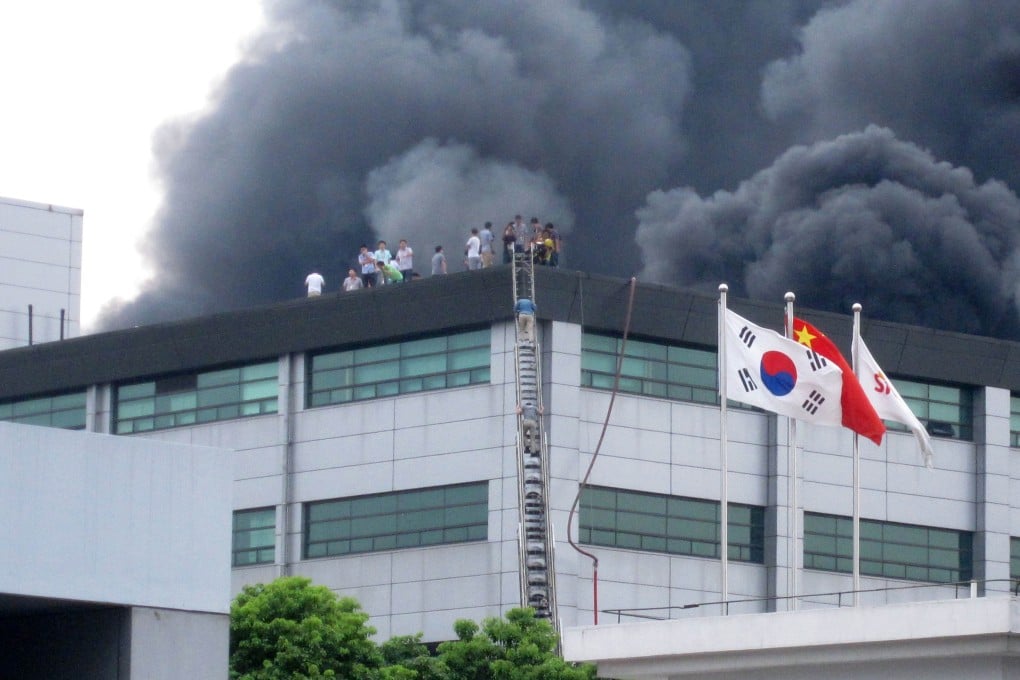 People take on the rooftop as heavy smoke rises from the SK Hynix facility in Wuxi, in Jiangsu province. Photo: AFP
