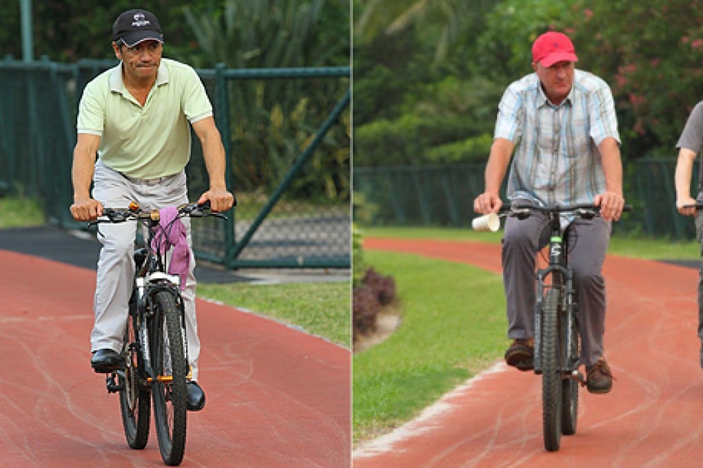 Trainers Tony Cruz and Tony Millard ride bicyles to watch their horses. Photos: Kenneth Chan