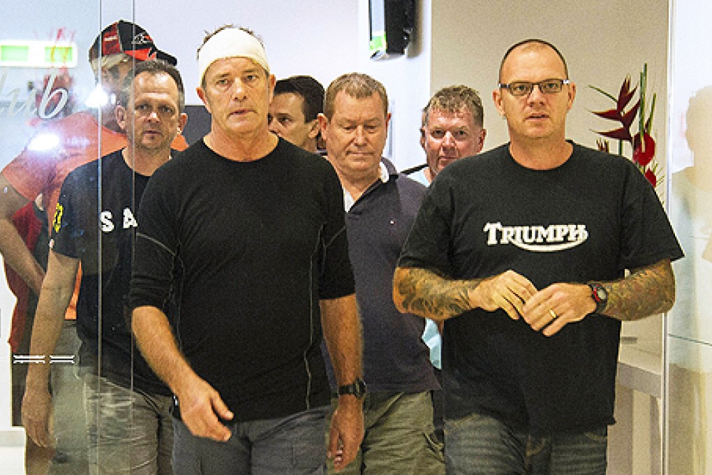 Injured trekkers Nick Bennett (front left), Peter Stevens (centre) and Steve Ward (right) arrive at the airport in Cairns, Queensland on Thursday following their brutal attack by bandits in Papua New Guinea. Photo: AFP