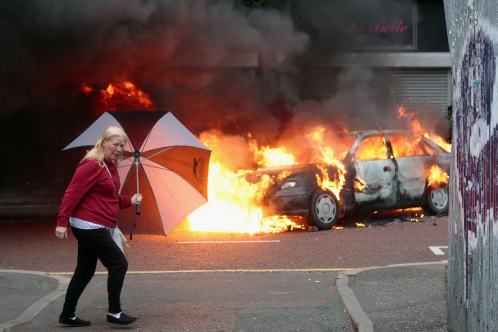 A woman walks past a burning car in the centre of Belfast. Amnesty said many abuses in Northern Ireland still remain hidden. Photo: AP