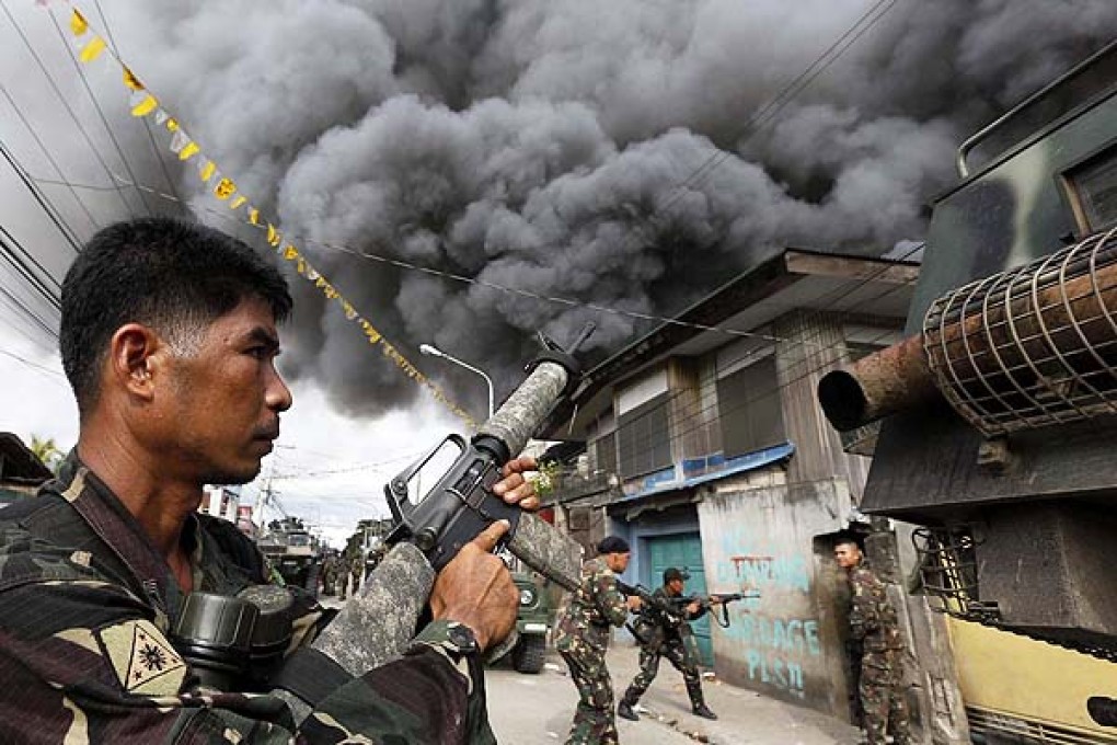 A fire rages as Filipino soldiers go into battle against separatist militants in Zamboanga where fighting erupted on Monday. Photo: EPA