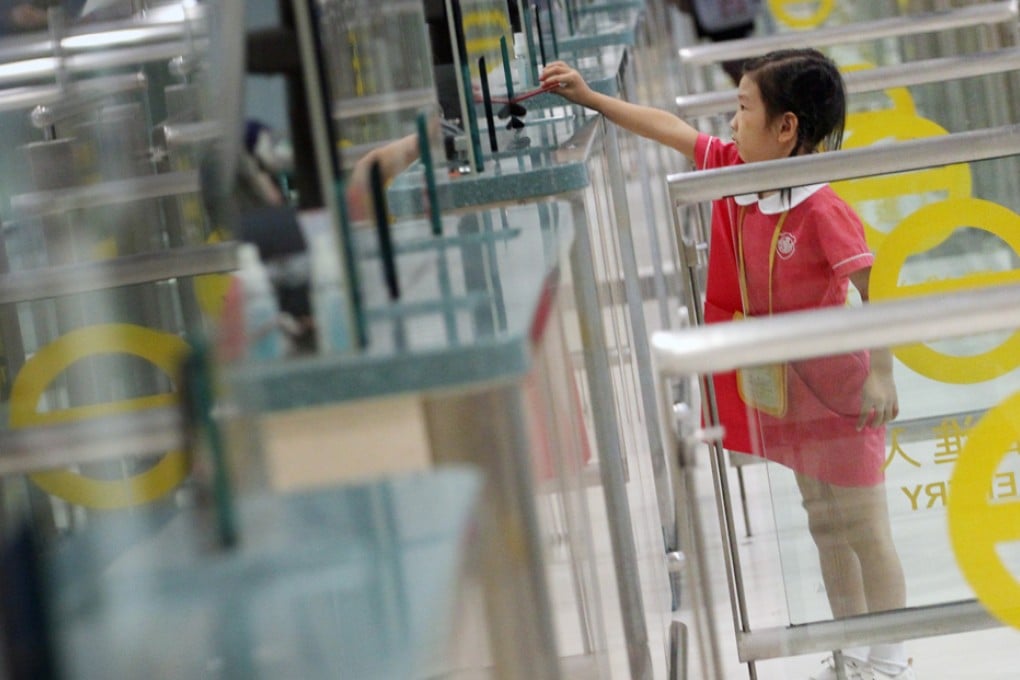A girl shows her identification card to an officer as she passes through Lok Ma Chau checkpoint to go to school. Photo: Felix Wong