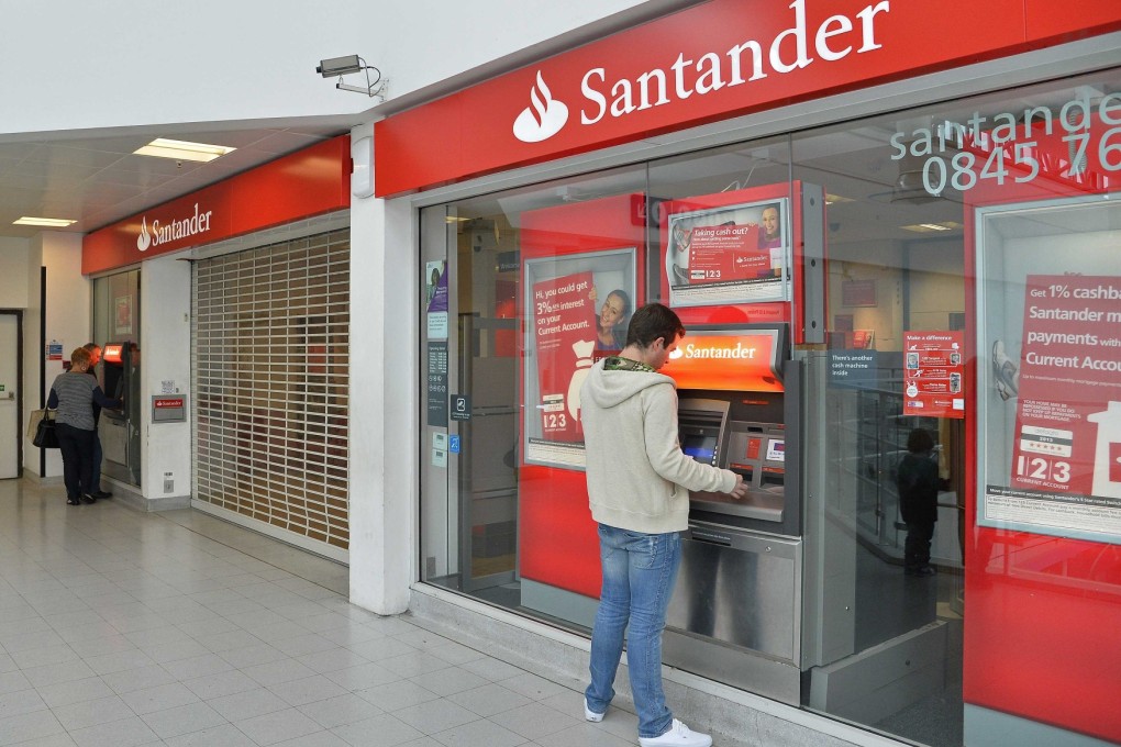 Customers use ATM machines at the Surrey Quays branch of Santander Bank, in south London. Four men have been charged over the Santander cyber plot. Photo: Reuters