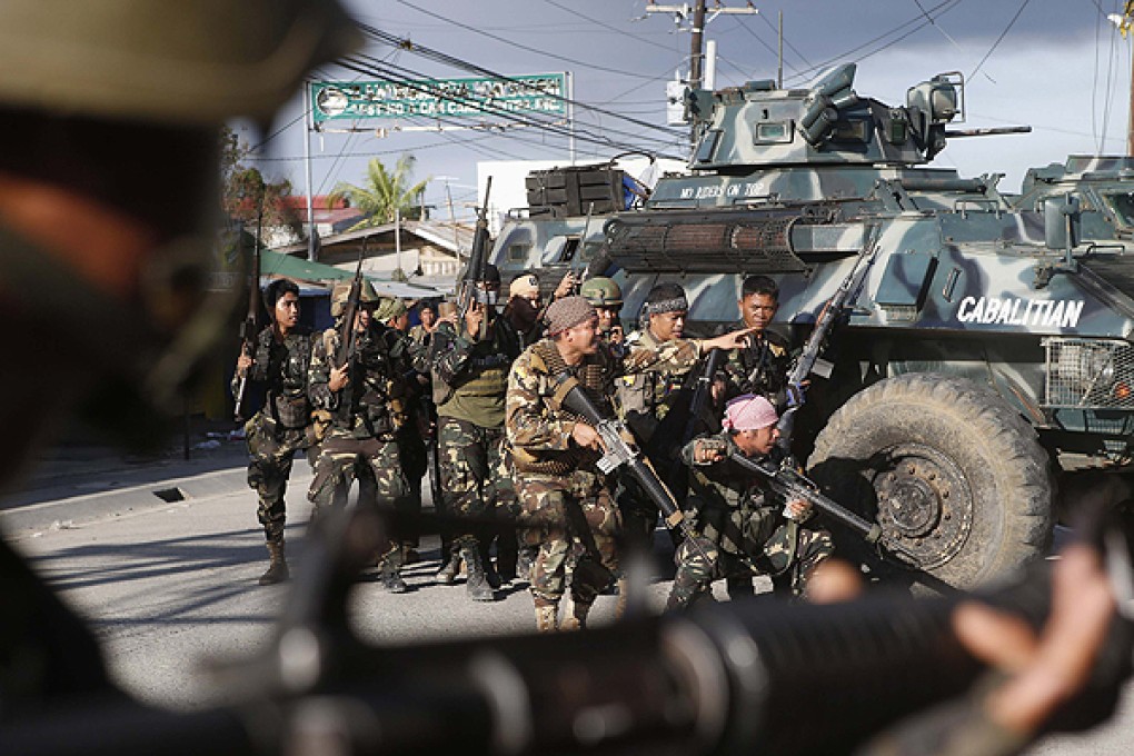 Government soldiers take cover beside armoured vehicles as they try to assault positions held by Muslim rebels in Zamboanga. Photo: Reuters