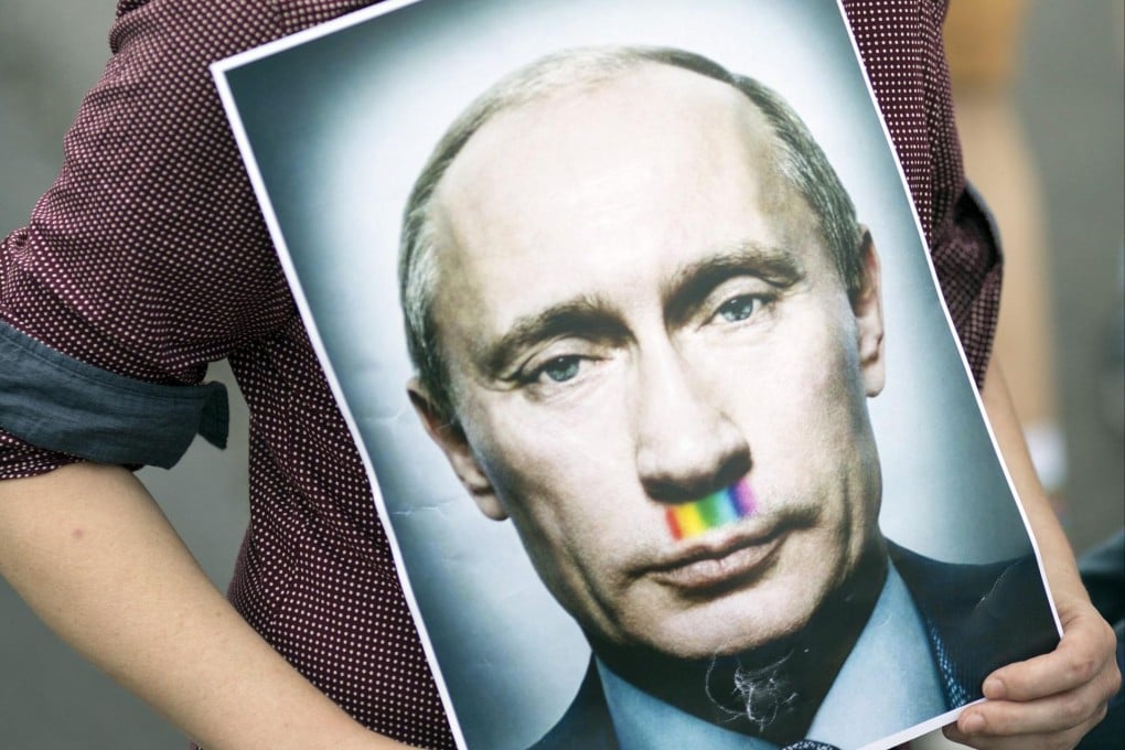 Protesters at a demonstration in Berlin show off a poster of Vladimir Putin with a rainbow-hued moustache. Photo: EPA