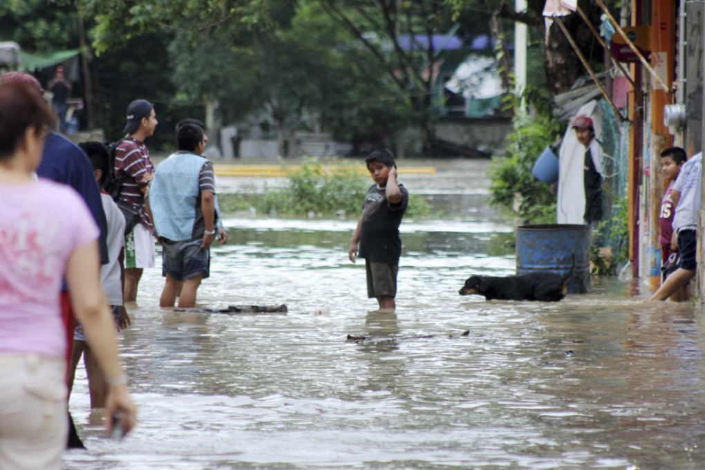 Residents wade through a flooded street in Poza Rica. Photo: Reuters