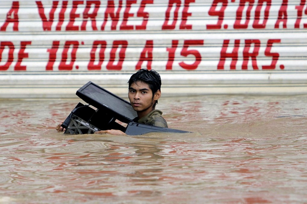 A man holds a stolen computer aloft in Acapulco. Photo: AFP