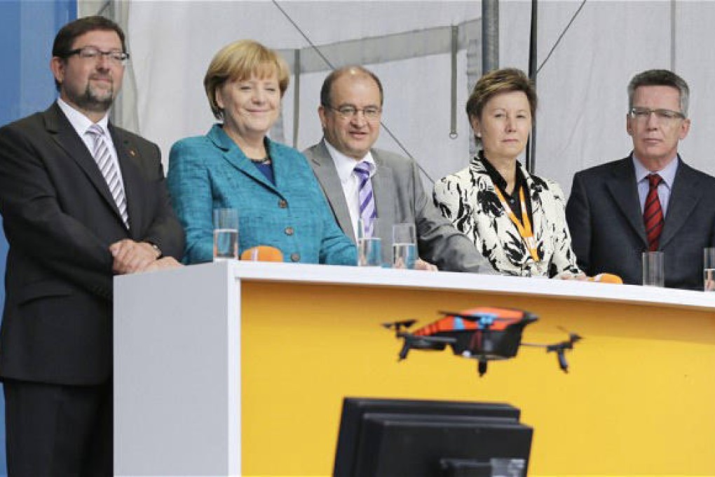 Chancellor Angela Merkel and Defence Minister Thomas de Maiziere watch the drone before it crashed in front of the stage. Photo: Reuters