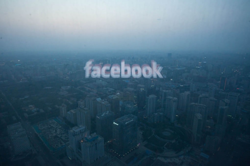 A computer screen that displays the logo of Facebook is reflected in a window before the Beijing skyline. Photo: AFP