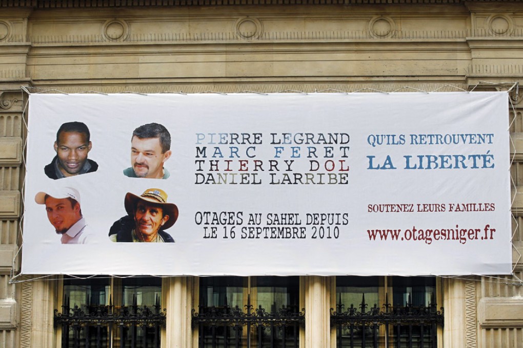 A banner with the portraits of the French hostages that were kidnapped in Niger three years ago. Photo: AP