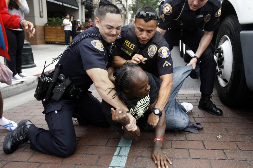 Pasadena police hold down a man who was upset when the deal fell through after he queued overnight for the coveted gadget. Photo: MCT