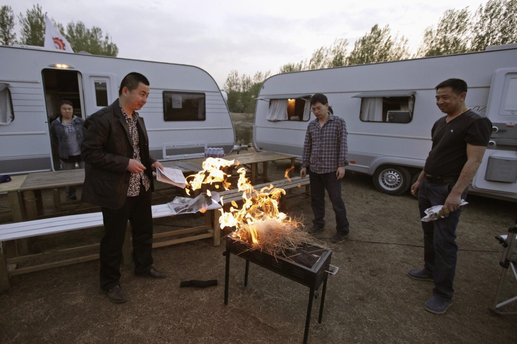 Caravan enthusiasts light a barbecue grill at an RV park outside Beijing. Photo: Reuters