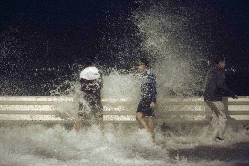 People react as waves surge past a barrier on the shore during Typhoon Usagi in Hong Kong. Photo: Reuters