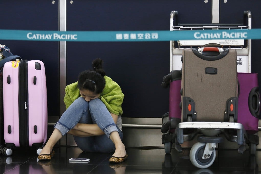 A passenger waits for flights to resume while sitting an airline counter at Hong Kong's international airport. Photo: AP