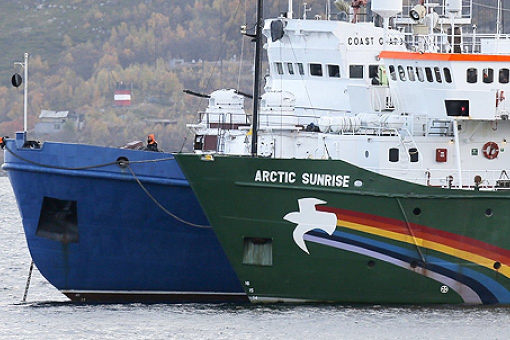 A crew member keeps watch aboard a Russian coast guard boat as the Greenpeace ship Arctic Sunrise is anchored next to it, in a small bay near Severomorsk, Russia, on Tuesday. Photo: AP