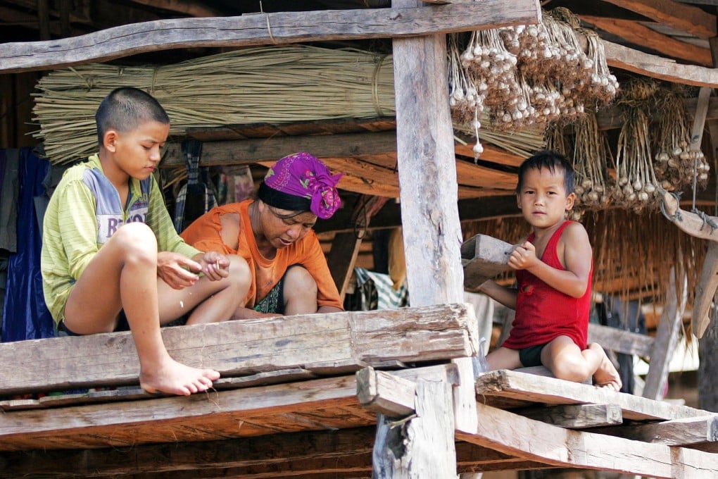 An Akha mother and her children in their house in a hill village in northwestern Laos. At the bottom of the opium supply chain, the Akha gain little from it. Photo: Andrew Chant