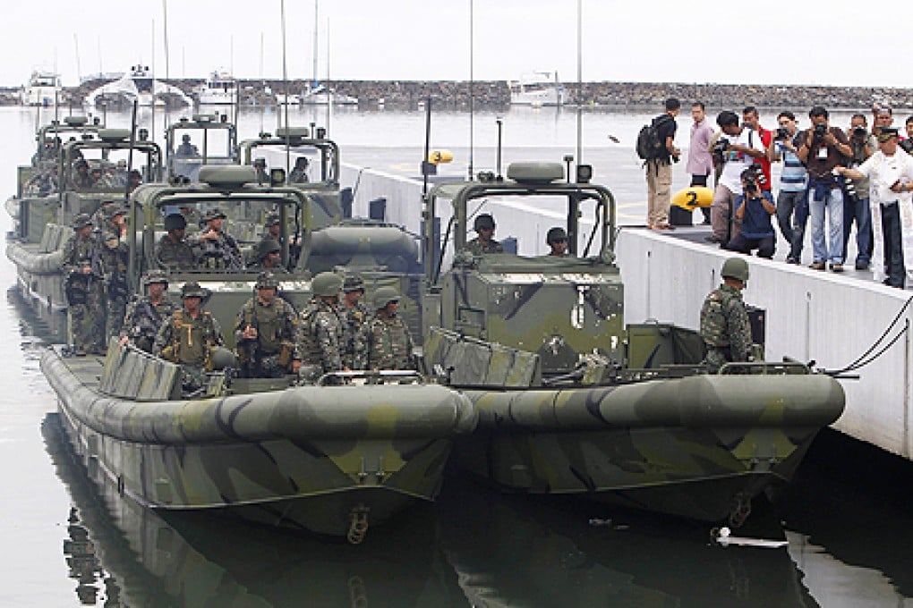 A Philippine Navy chaplain sprinkles holy water to bless the Navy's six new small-unit riverine crafts donated by the US government, during a handover ceremony at navy headquarters in Manila on Wednesday. Photo: Reuters