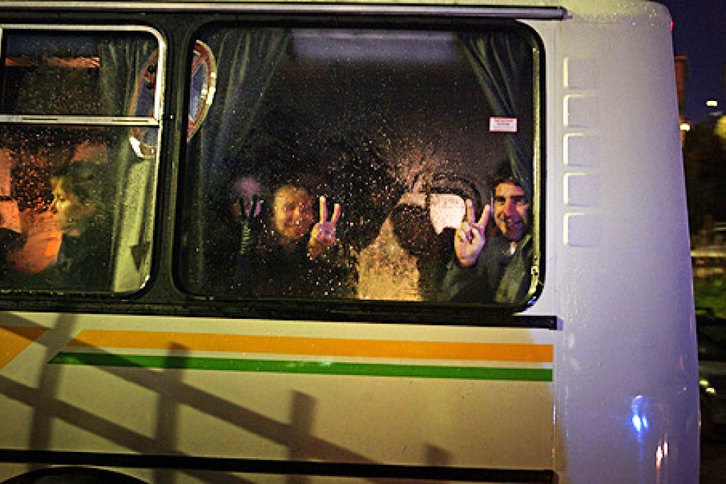 Greenpeace activists flash V-signs for victory from a bus window as they arrive at the offices of the Russian Investigative Committee in Murmansk. Photo: AFP