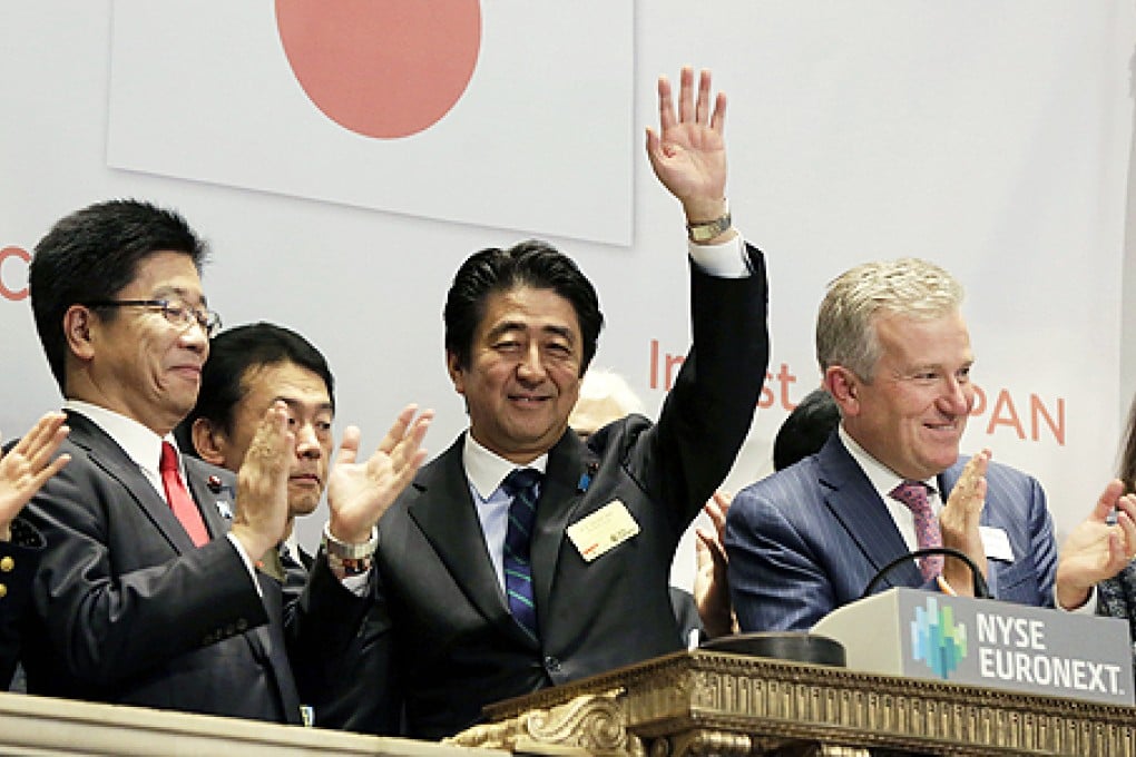 Japan's Prime Minister Shinzo Abe (centre) waves after ringing the closing bell, with NYSE CEO Duncan Niederauer (right) at the New York Stock Exchange, on Wednesday. Photo: AP