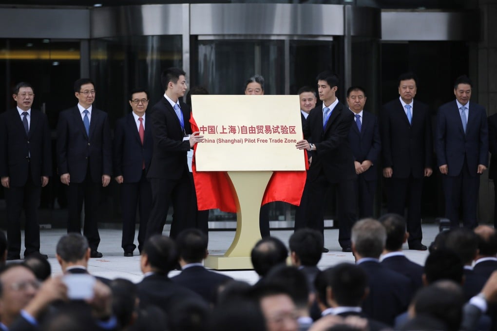 Men remove a sign after the inauguration of Shanghai's Free Trade Zone in Pudong district, Shanghai. Photo: Reuters