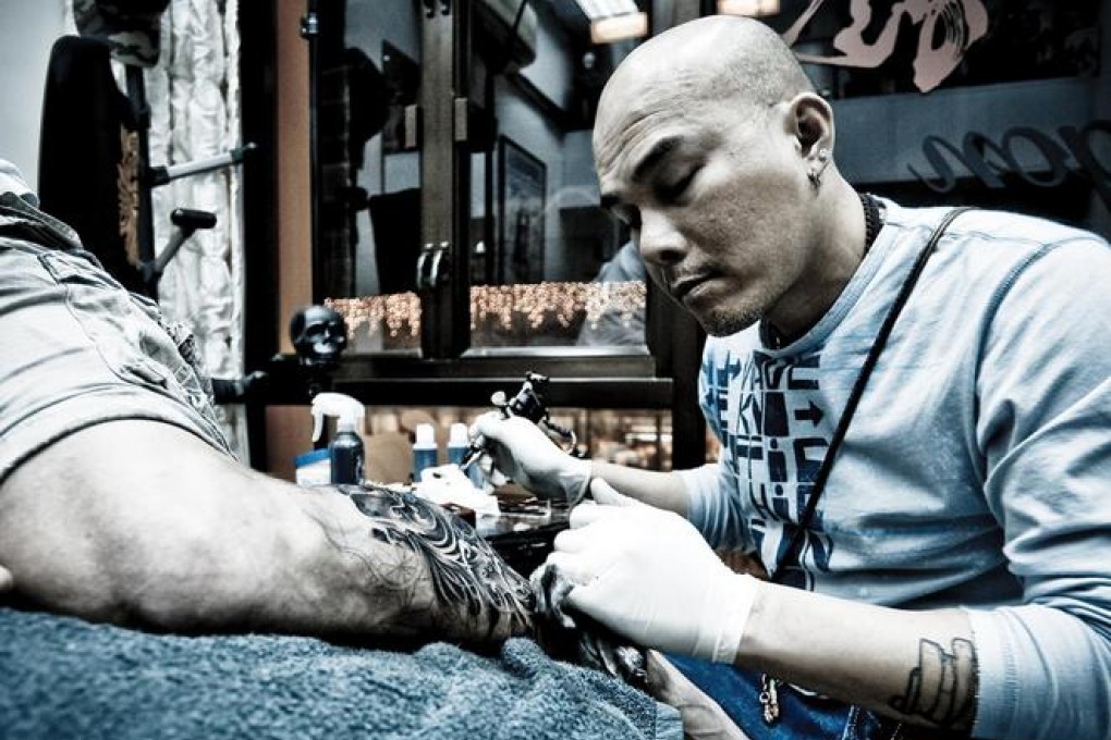 Gabe Shum applies some ink to his tattoo convention partner, Jay FC. Photo: Red Dog Studio