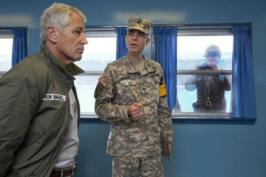 Chuck Hagel listens to Colonel James Minnich as a North Korean soldier takes a photograph. Photo: AFP