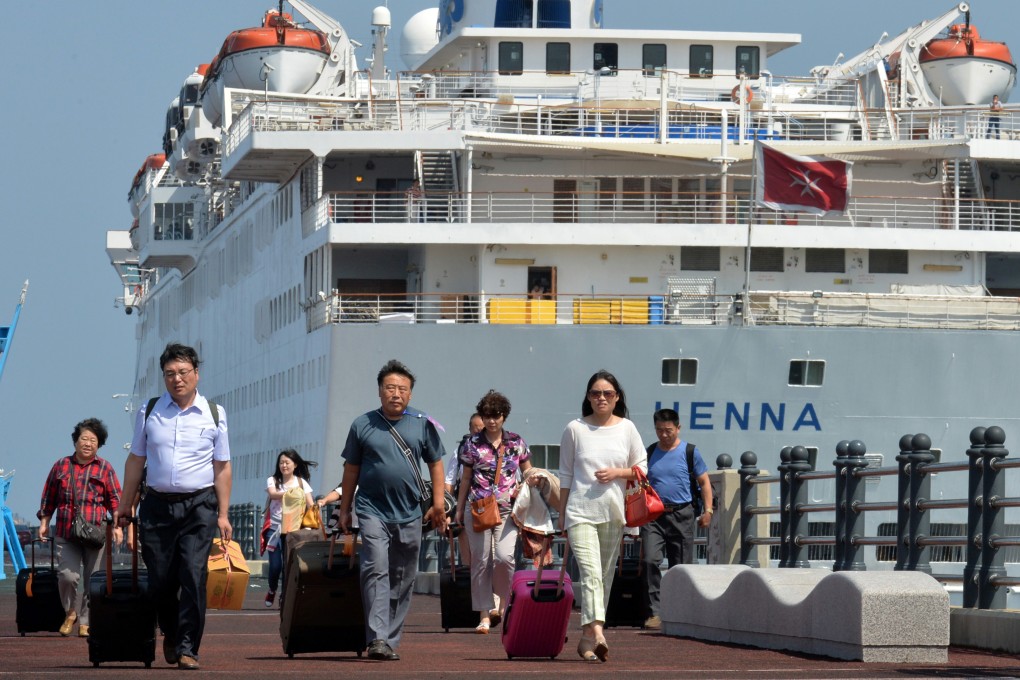 Passengers leave the Chinese cruise liner Henna for the airport on Jeju after a corporate legal dispute left them stranded on the South Korean island last month. Photo: AP