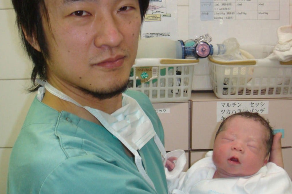 Doctor Kawamura poses with the baby after a woman gave birth following his treatment. Photo: AP