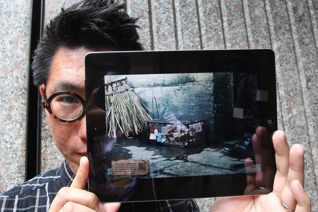 Kwong Chi-kit holds a tablet displaying one of the model cage homes designed to draw attention to the severity of the housing problem. Photo: Jonathan Wong