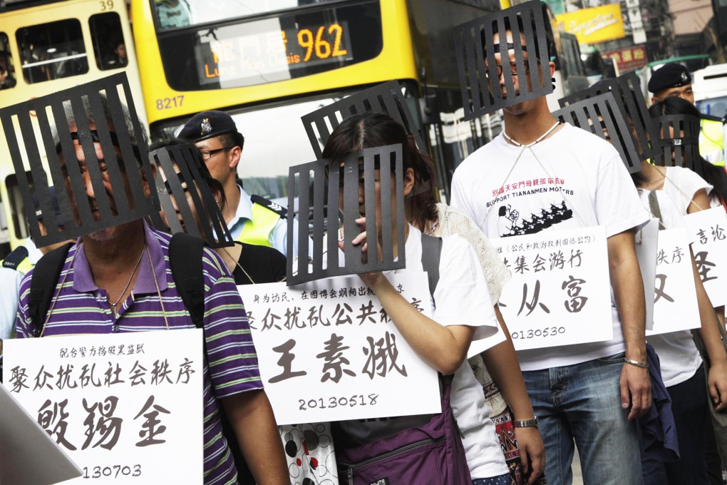 Protesters wear cages to symbolise political prisoners. Photo: David Wong