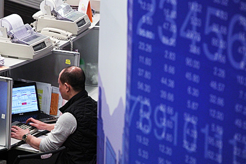 A trader looks at financial figures at the trading hall of the Stock Exchange of Hong Kong in Central. Photo: David Wong