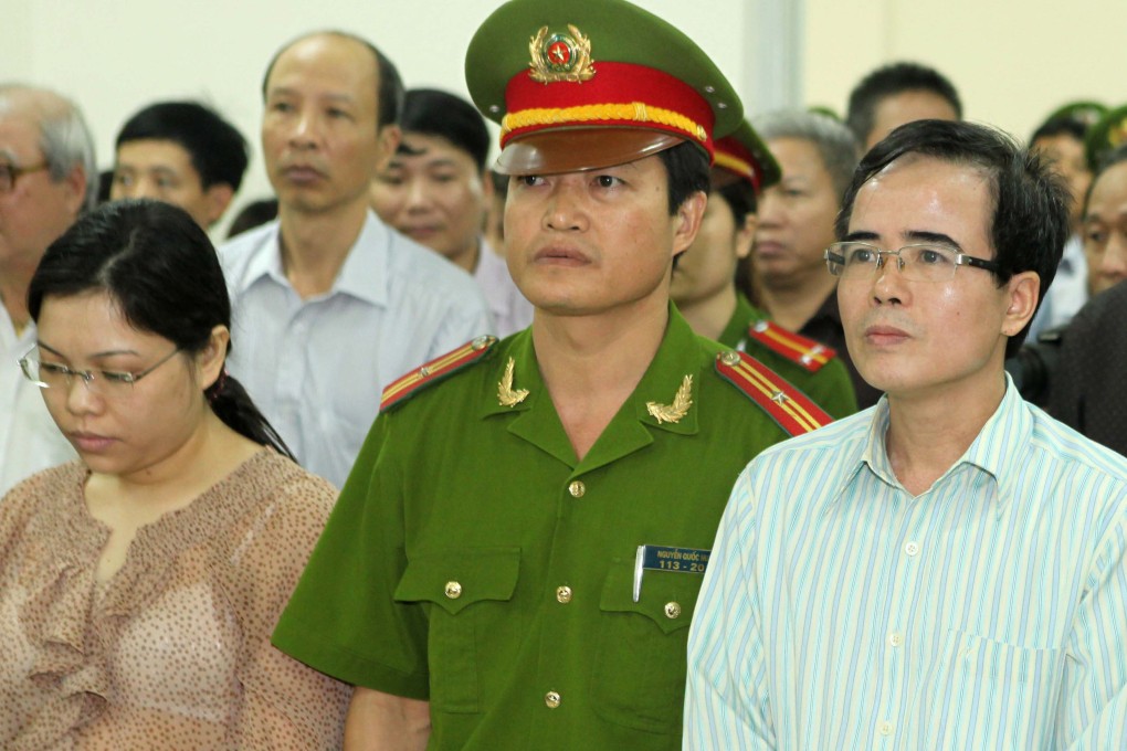 Lawyer Le Quoc Quan (right) and accountant Pham Thi Phuong stand with a policeman during their trail at a court in Hanoi. Photo: Reuters