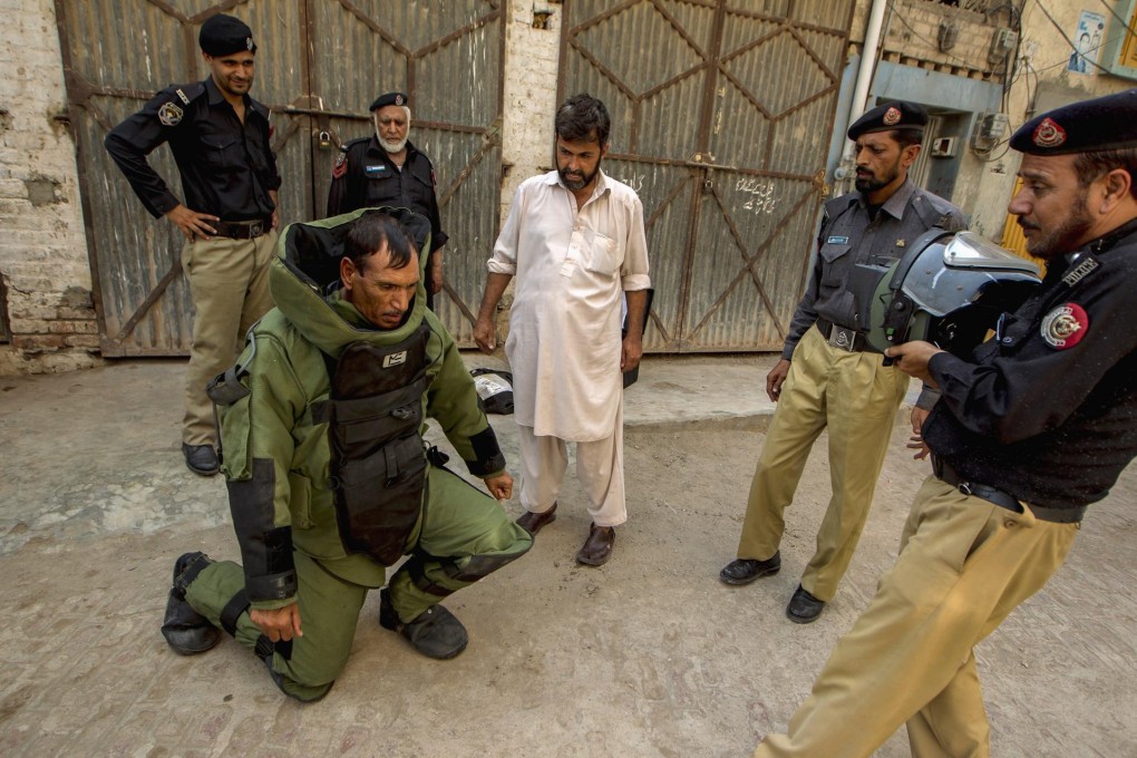 A bomb-disposal technician rests under the weight of a heavy protective suit during a search in Peshawar. Photo: Reuters