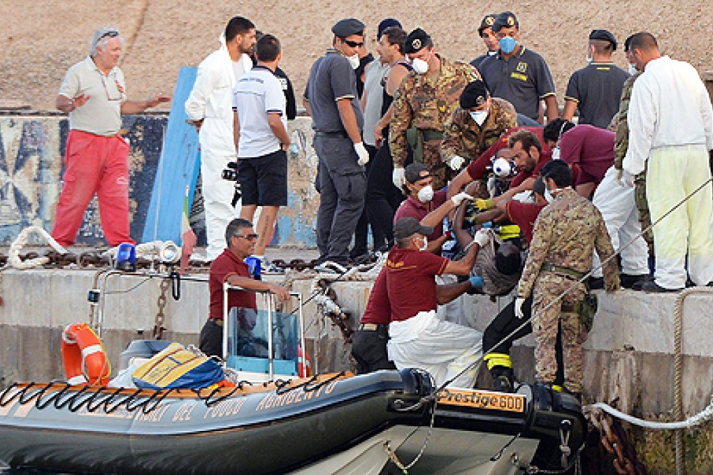 Italian rescue workers recover a dead body from a boat at the port of Lampedusa, Italy, on Thursday. Photo: EPA