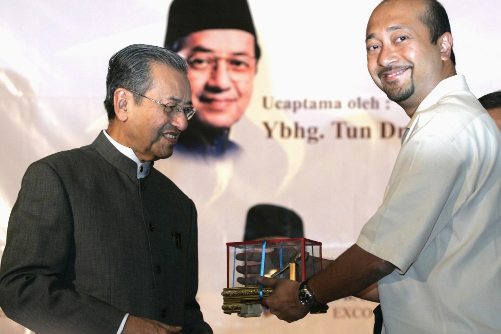 Mukhriz Mahathir receives a memento from his father Mahathir Mohamad in Petaling Jaya. Photo: Reuters