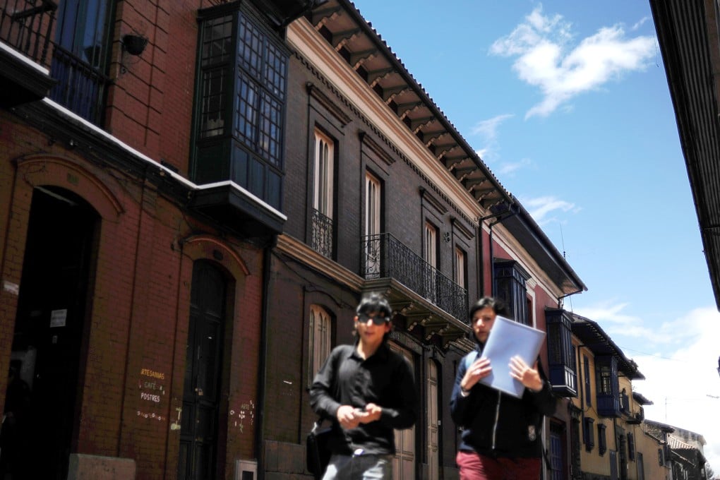 Two young women walk down a street in the historic neighborhood of La Candelaria in Bogota. Photo: AP