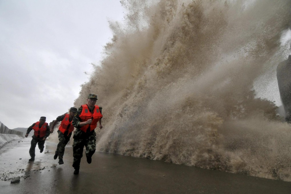 Frontier soldiers run in Wenling , Zhejiang province, yesterday as the storm surge from Typhoon Fitow hits the coast. Photo: Reuters