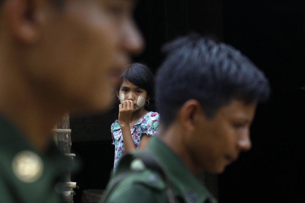 A frightened Muslim girl watches from the doorway of her home as soldiers walk past in a village near Thandwe. Photo: Reuters