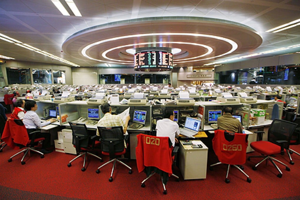 Floor traders study stock prices at the Hong Kong Stock Exchange. Chinese financials were broadly higher in Hong Kong, but mixed in the mainland. Photo: AP