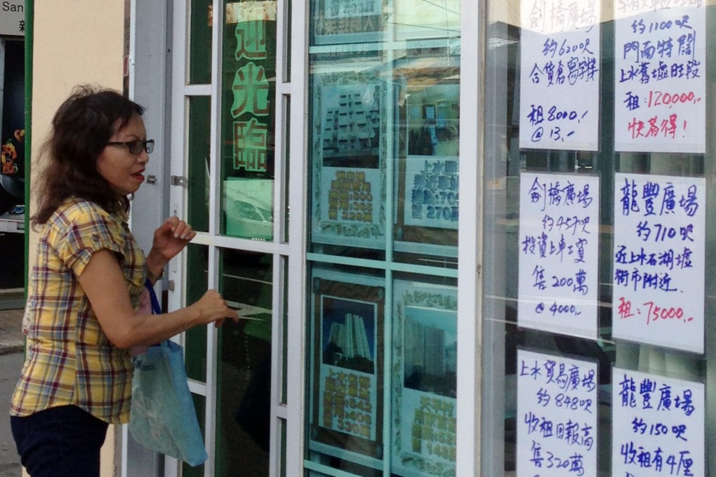 A woman checks out the apartments for rent advertised in a property agent's window in Sheung Shui. Photo: Candy Chan