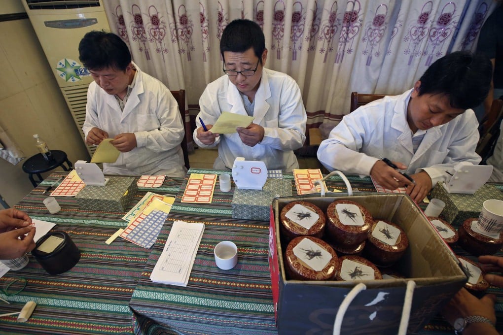 Judges prepare labels before they measure the weights of crickets during the Beijing Cricket Fighting Competition