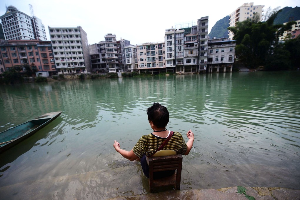 A woman soaks her feet in the Panyang River in Bama, which has seen an influx of cancer patients and others with serious illnesses seeking a cure. Photo: Imaginechina
