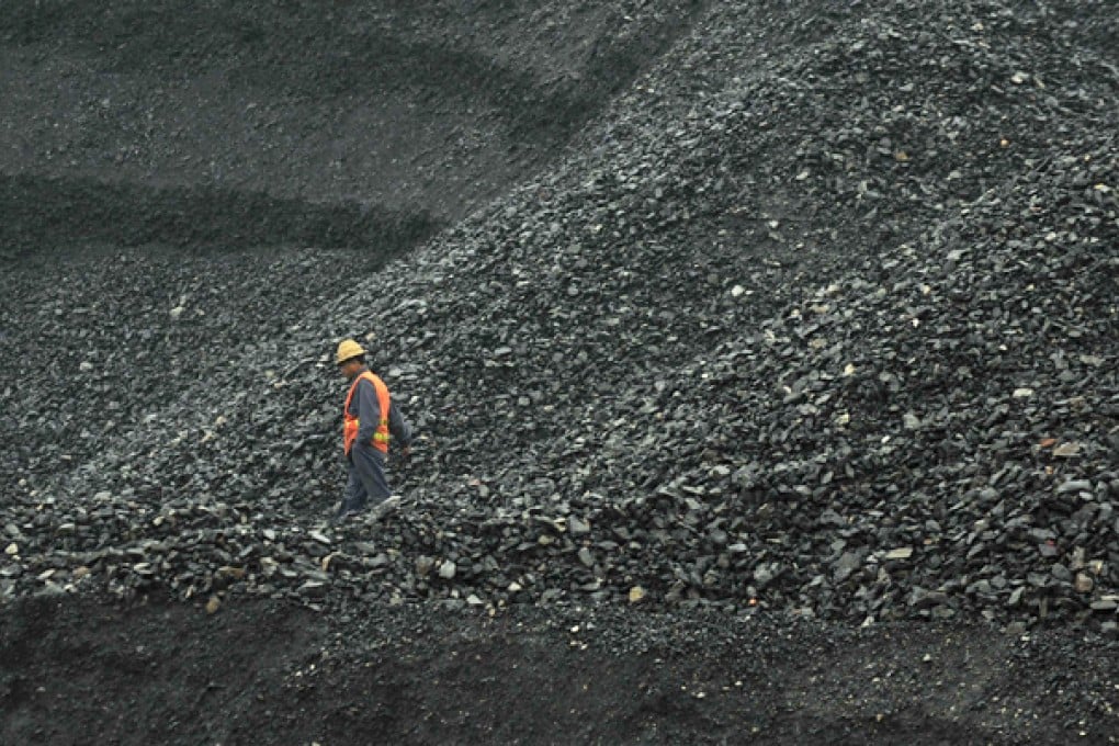 A labourer walks amid piles of coal at an opencast coal mine in Fuxin, Liaoning province. Photo: Reuters