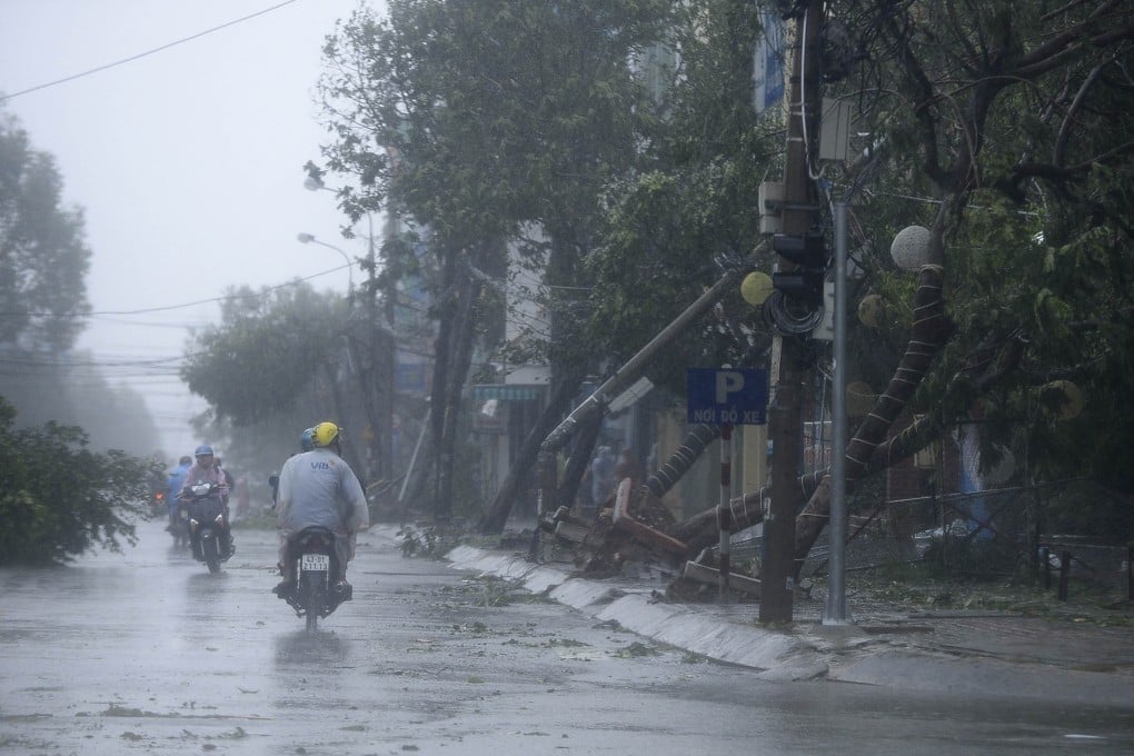 Motorcyclists ride past along fallen trees, caused by Typhoon Nari, along a street in Vietnam's central Danang city. Photo: Reuters
