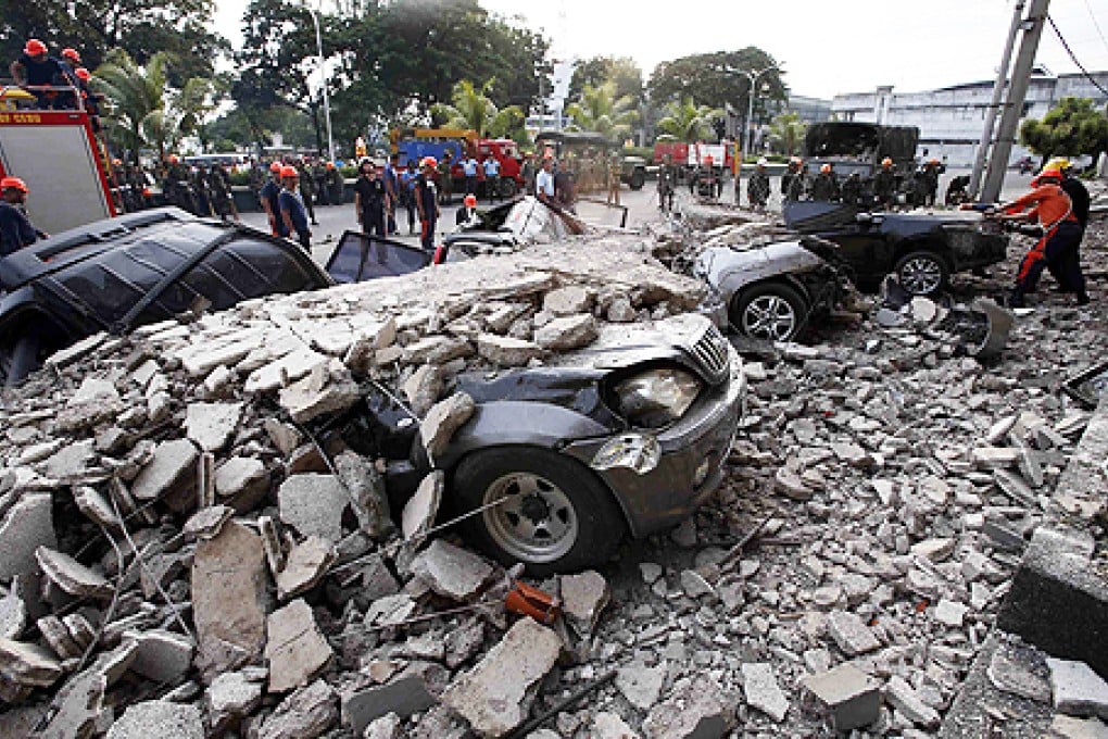 Firefighters stand near destroyed vehicles covered with rubble after an earthquake struck Cebu city, in central Philippines on Tuesday. Photo: Reuters